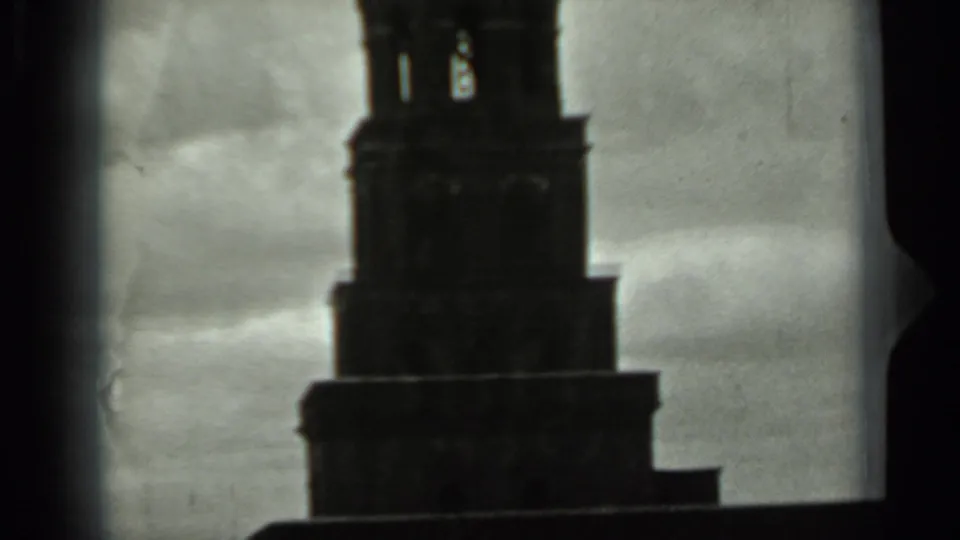1963 Russia 8mm frame of a tall tower's upper tiers and open spire section silhouetted against a gray sky.