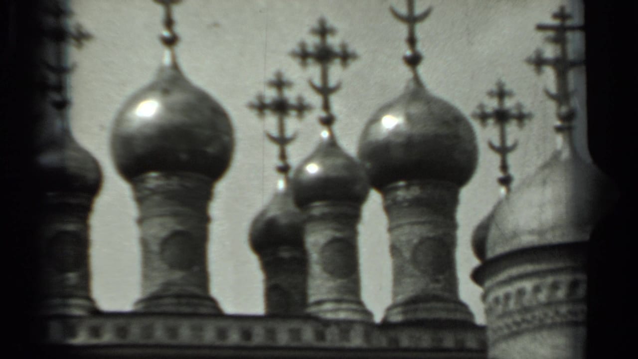 Close view of onion domes and Orthodox crosses against a pale sky.