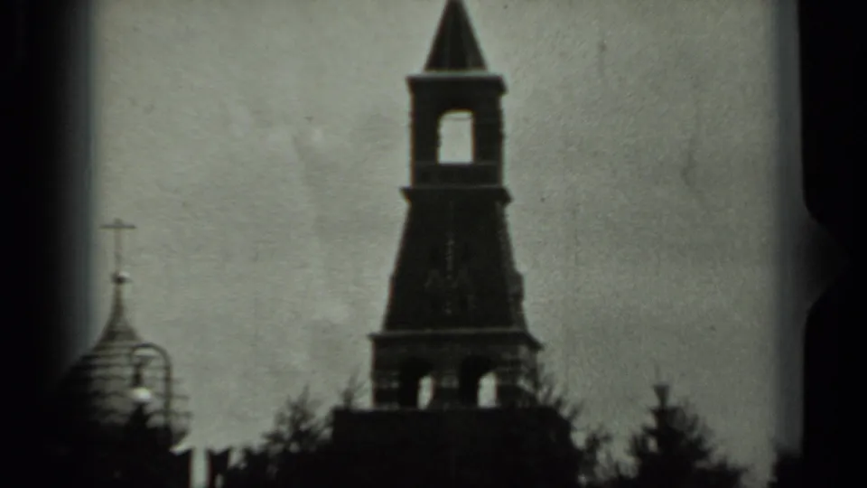 1963 Russia 8mm frame showing a bell tower, smaller church domes, and tree silhouettes under a bright sky.