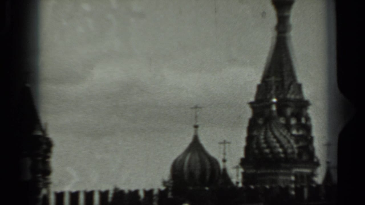 Black-and-white view of onion domes and spires behind dark film gate edges.