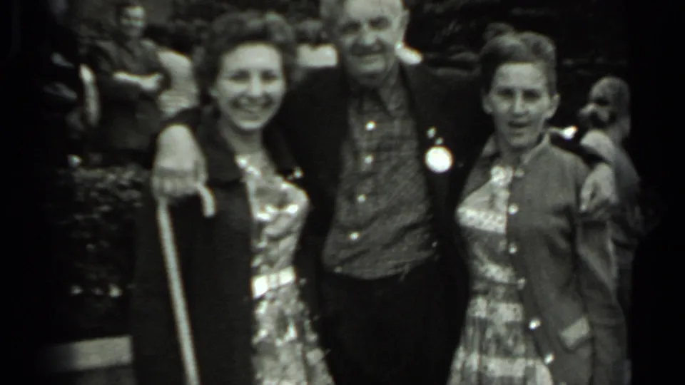 1963 Russia home-movie frame of three adult visitors posing outdoors, with domes and other people in the background.