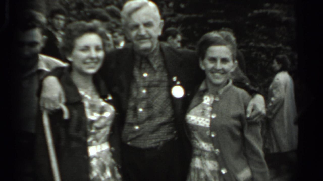 A posed 1963 Russia home-movie frame shows three adults smiling at the camera, with another person partly visible near the edge.