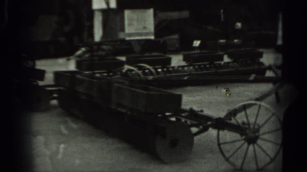 Wheeled agricultural cart with compartments seen in a dim indoor room.