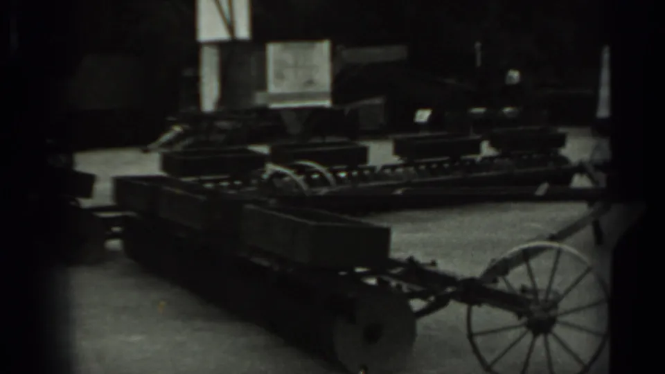 Final 1963 Russia 8mm frame showing the wheeled metal farm cart under low light, with storage equipment and windows in the background.