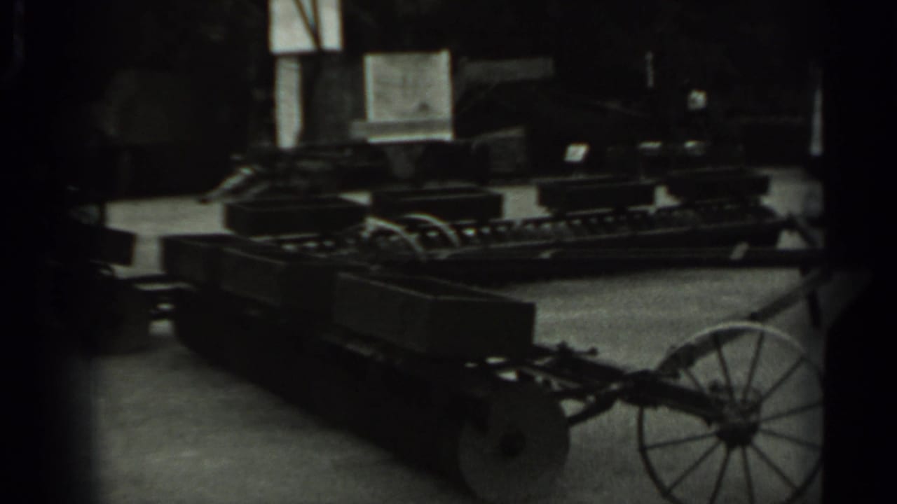 Similar dark view of wheeled machinery with a large spoked wheel at right.