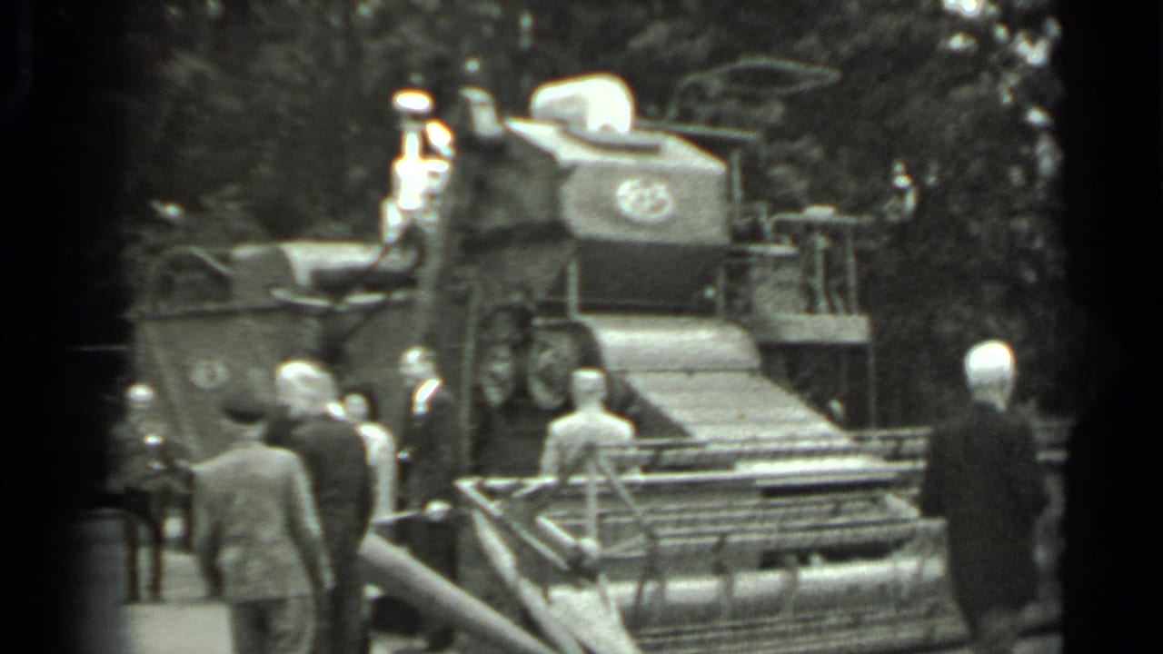 Visitors stand beside a large combine harvester at an outdoor display.