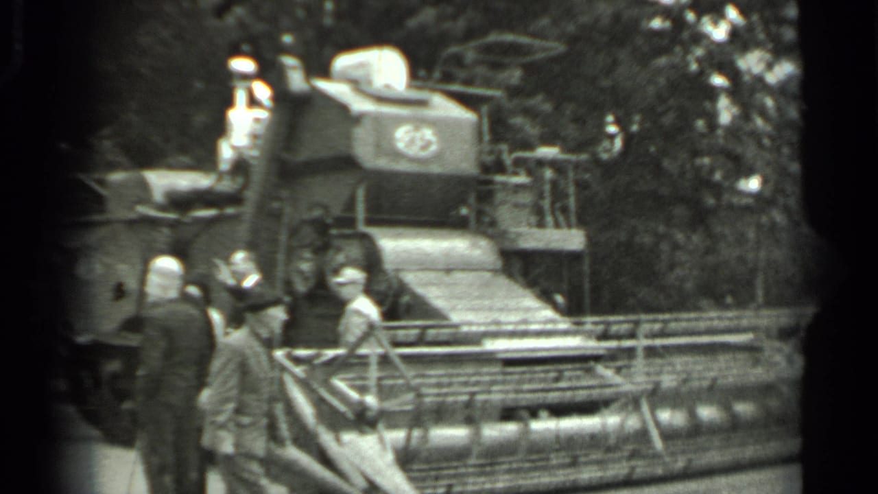 Several visitors inspect the front of a combine harvester outdoors.