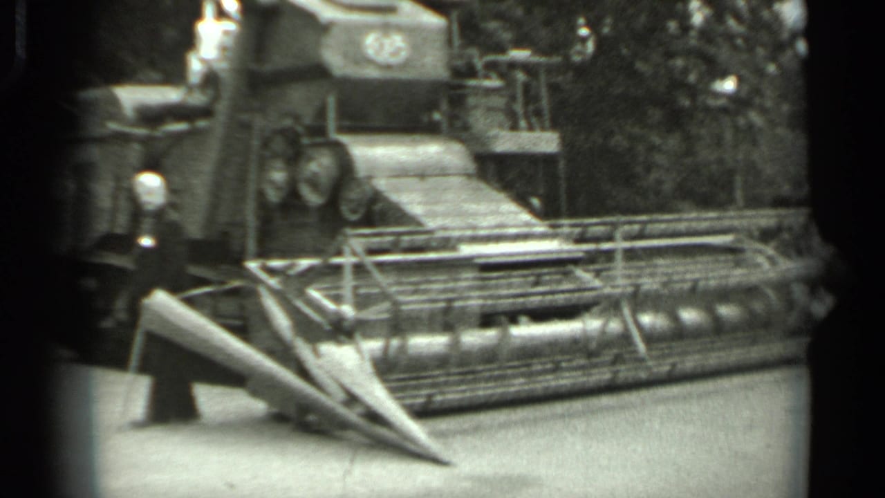 Large tracked machine fills the frame with its front cutting header visible.