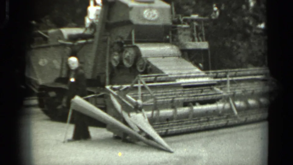 1963 Russia frame with a capped man beside a tracked agricultural machine, likely at an exhibition display.
