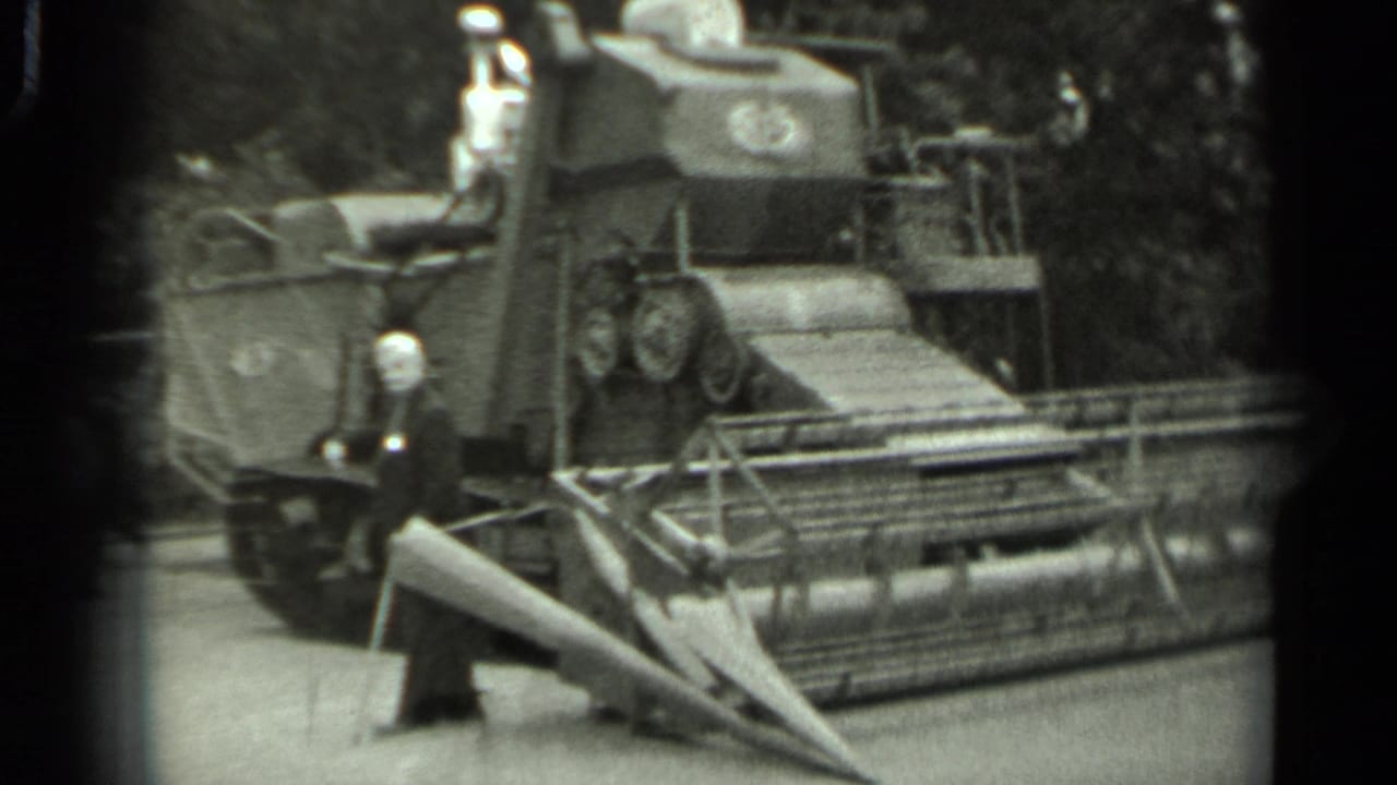 Tracked farm machine and front header seen close up with a man standing at the side.