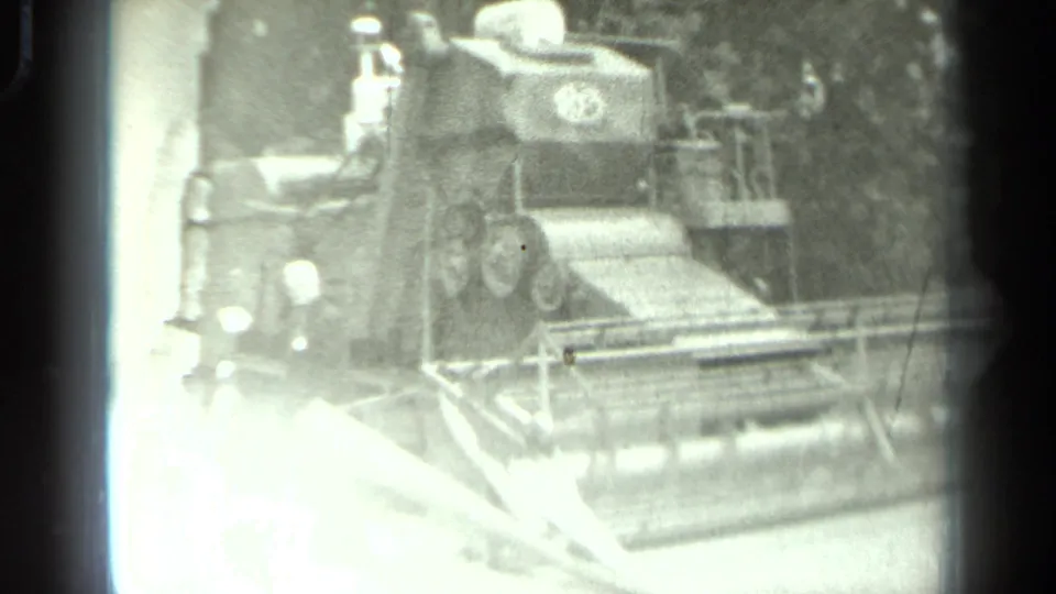 High-contrast 1963 Russia 8mm frame showing people near the front of a tracked agricultural machine, partly washed by exposure flare.