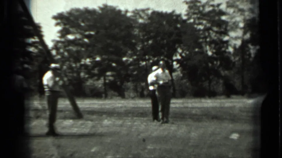 1963 Russia home-movie frame showing two people in an open field after the machinery view, with trees in the background.