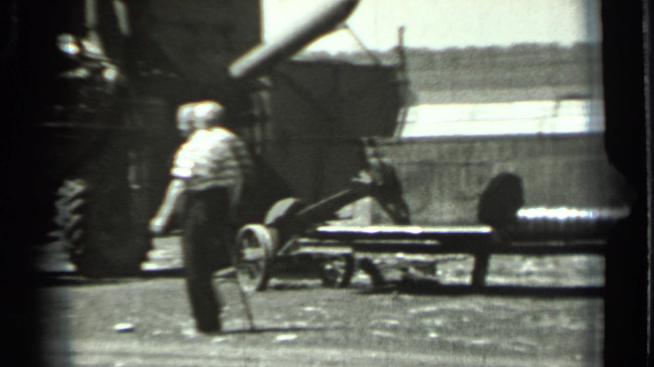 1963 Russia 8mm frame showing a man walking past large agricultural machinery in a rural work area.