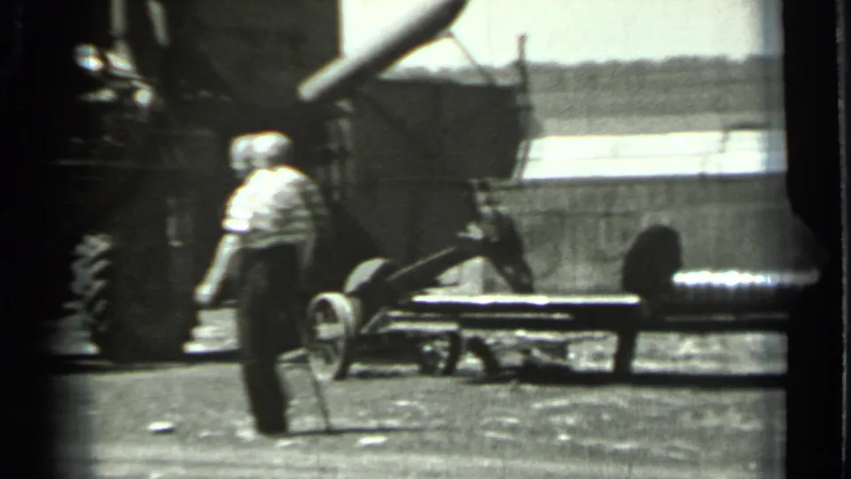 1963 Russia 8mm frame showing a man walking past large agricultural machinery in a rural work area.