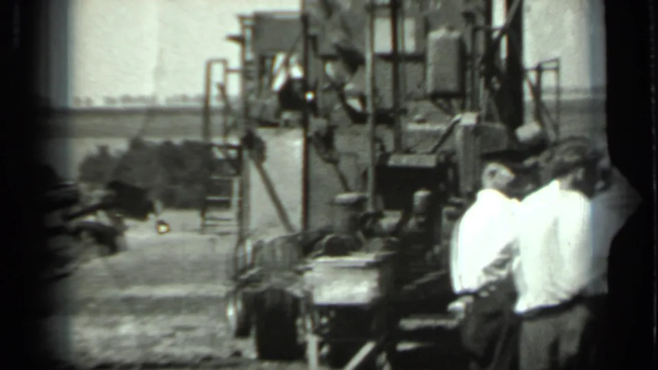Men gather around a large agricultural machine during apparent maintenance in 1963 Russia footage.