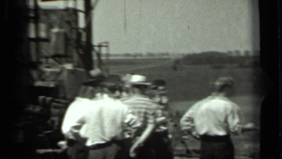 Workers in light shirts and hats stand beside farm machinery in a rural field, matching the 1963 Russia metadata.