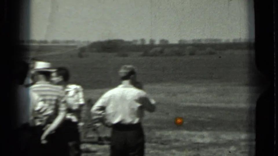 1963 Russia 8mm frame showing adult men in casual shirts and hats standing in a rural field near equipment out of frame.