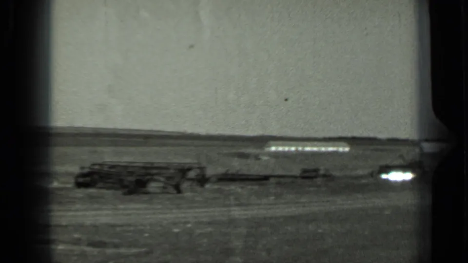 1963 Russia 8mm frame of low field equipment or vehicles on open terrain, with a bright film artifact near the right edge.