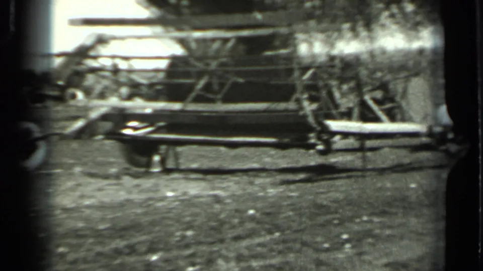 Close black-and-white 8mm view of a wheeled agricultural implement, possibly a plow or planting rig, on rural ground in Russia.