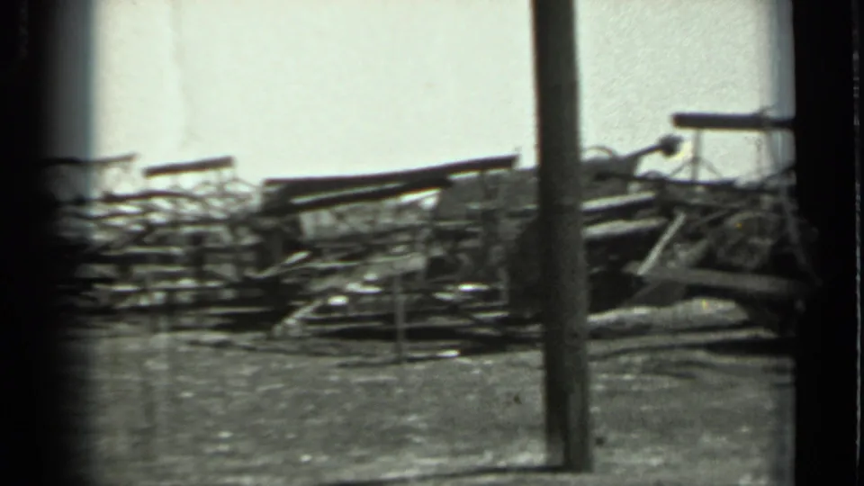 1963 Russia 8mm frame with stacked metal parts and a vertical pole crossing the foreground of the field view.