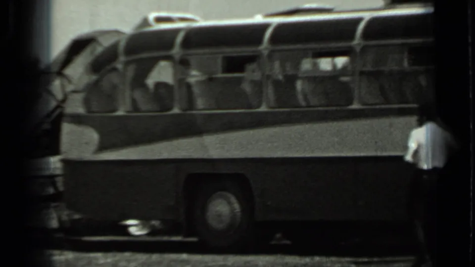 Grainy 1963 Russia home-movie frame showing a large rounded bus and a man in a light shirt near the vehicle.
