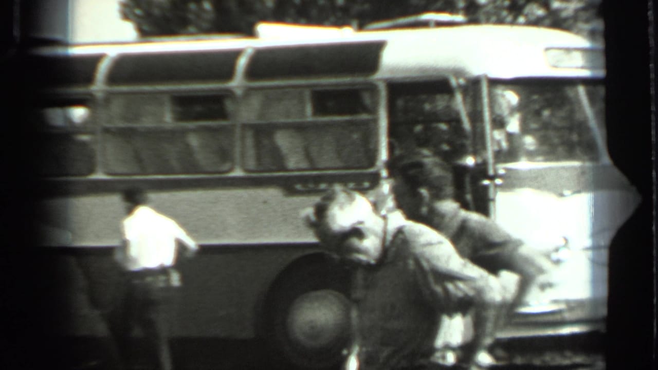 1963 Russia 8mm frame showing adult men near a Soviet-era bus, with the open front door area and side windows visible.