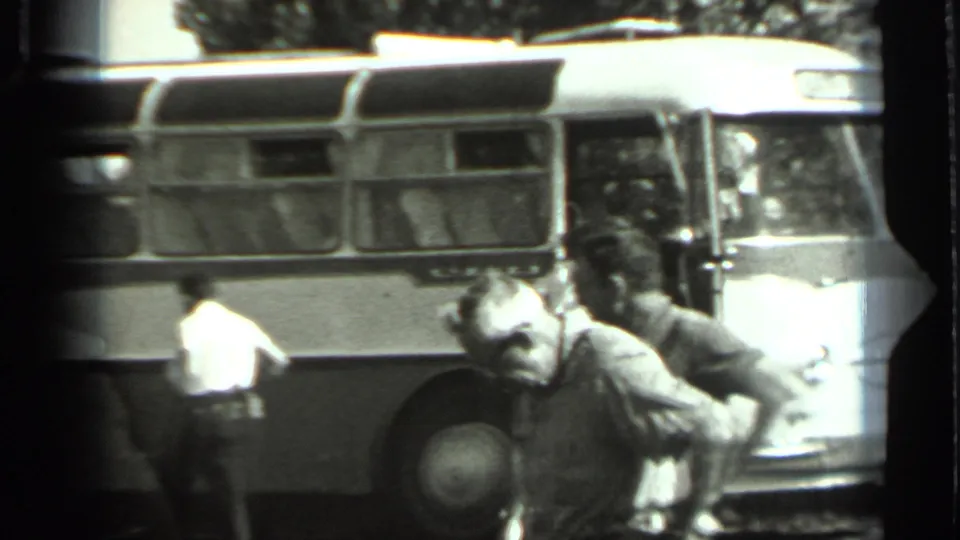 1963 Russia 8mm frame showing adult men near a Soviet-era bus, with the open front door area and side windows visible.