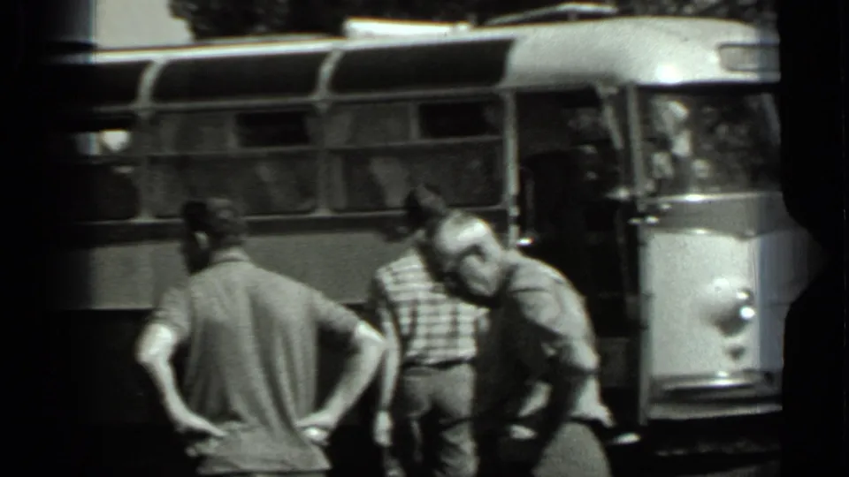 1963 Russia 8mm frame showing adult men beside the bus door and side windows, captured from an informal home-movie angle.