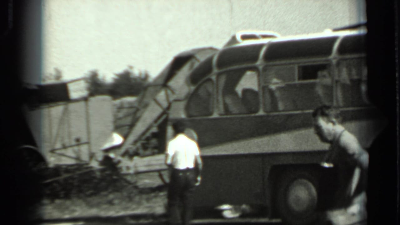 Adults near a bus or coach beside a rural field.