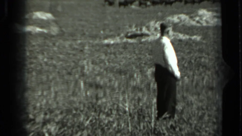 A man in a light shirt and dark trousers appears in profile in a rural field in 1963 Russia footage.
