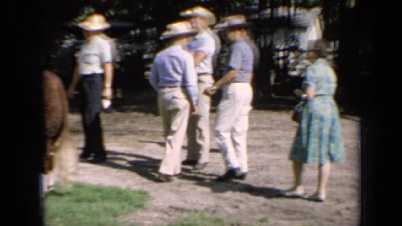 Kansas 1964 fairground view with adults in hats and a woman in a blue dress near Hereford cattle.