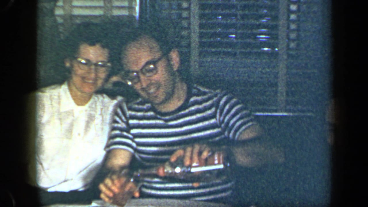 Young woman in a white blouse and man in a striped shirt sit together at a table.