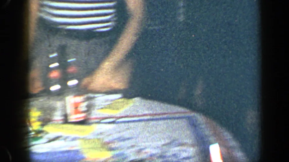 1948 New York party frame showing a tabletop with bottles, food or serving items, and a standing adult guest in a private interior.