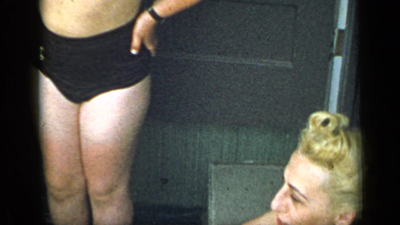 1948 New York home-movie frame showing a woman in a black swimsuit beside a seated blonde woman in a private outdoor area.