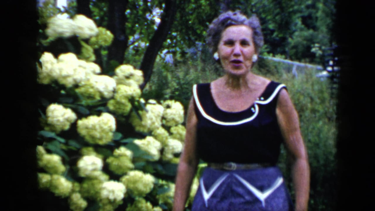 Woman standing in a garden beside pale hydrangea blooms.
