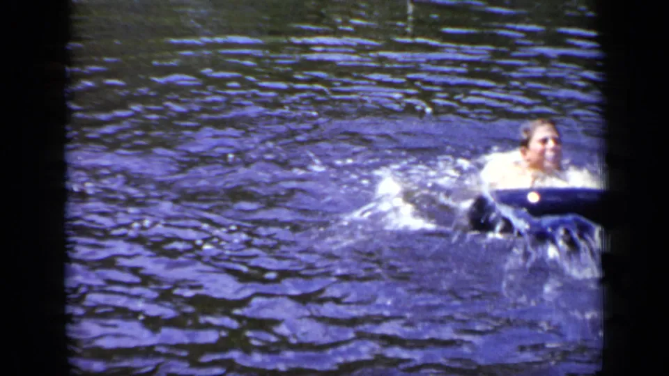 1948 New York home-movie frame with the swimmer moving beside a blue inner tube as water splashes across the surface.