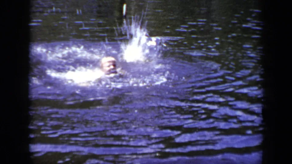 1948 New York home-movie frame showing the swimmer partly submerged as a bright splash rises in the dark water.