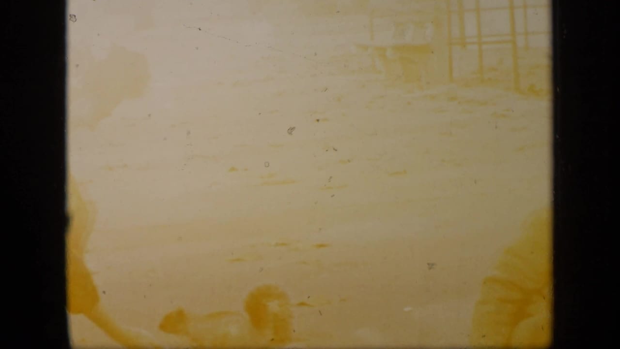 Faded yellow frame with a woman bending toward the ground near a small animal.