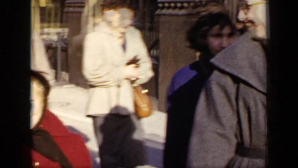 A handheld 1948 New York frame shows women walking on a city sidewalk, partly blurred by motion and bright sun.