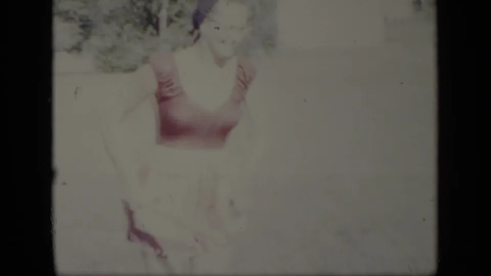 The woman appears closer to the camera in this 1948 New York home-movie frame, with her swimsuit visible against a washed-out sunny yard.