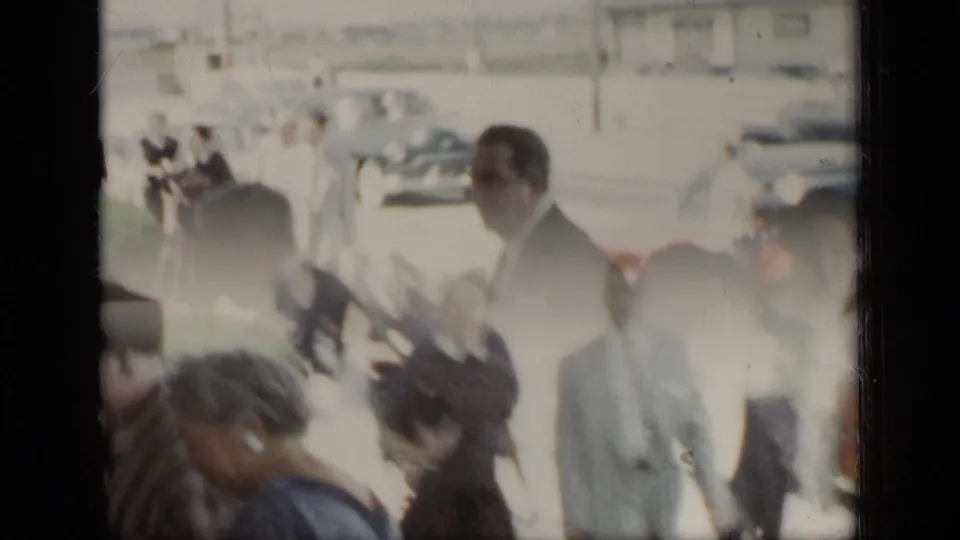 A suited man and several adults move through a bright outdoor area in 1948 New York home-movie footage.