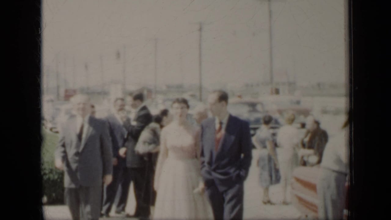 Bride and groom walk with wedding guests along an outdoor path.