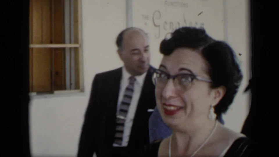 A smiling woman with glasses appears close to the camera, with a suited man and building wall behind her in the 1948 New York footage.