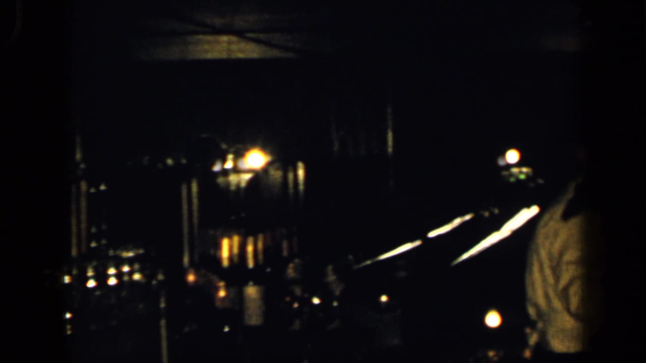 A dim 1948 New York night frame shows bridge or city lights with a man in a light shirt at the edge of the shot.