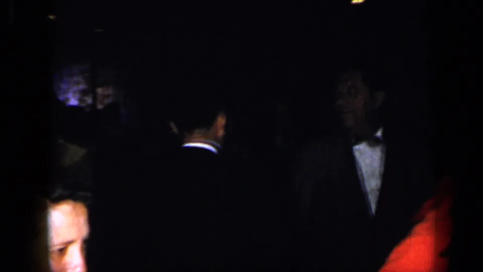 A tuxedoed man and other guests are visible in a dark 1948 New York formal gathering scene.