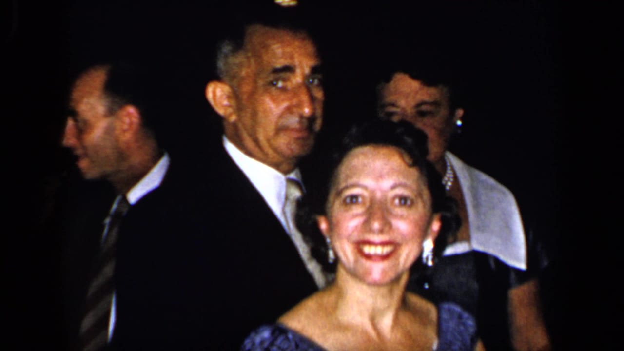 Adults in formal attire face the camera at a dim indoor party.