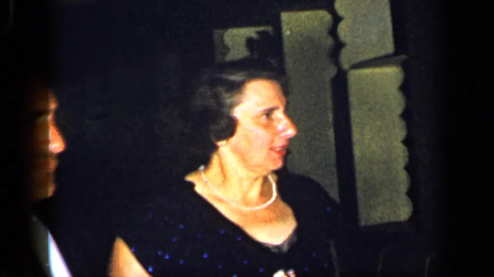 1948 New York frame of an adult woman in a dark formal dress and pearl necklace looking off-camera.
