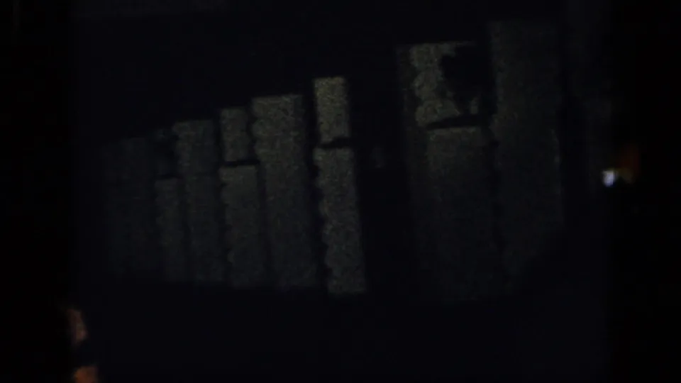 Dim 8mm frame from the New York 1948 clip showing a dark indoor setting with faint wall forms and little discernible action.