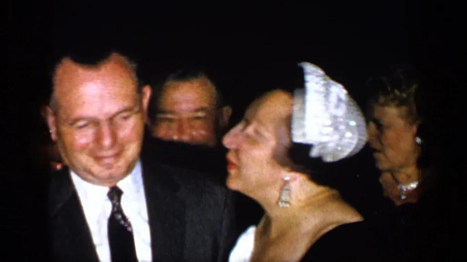 The woman in a decorative headpiece leans toward a suited man, appearing to kiss or speak near his cheek in the 1948 New York scene.