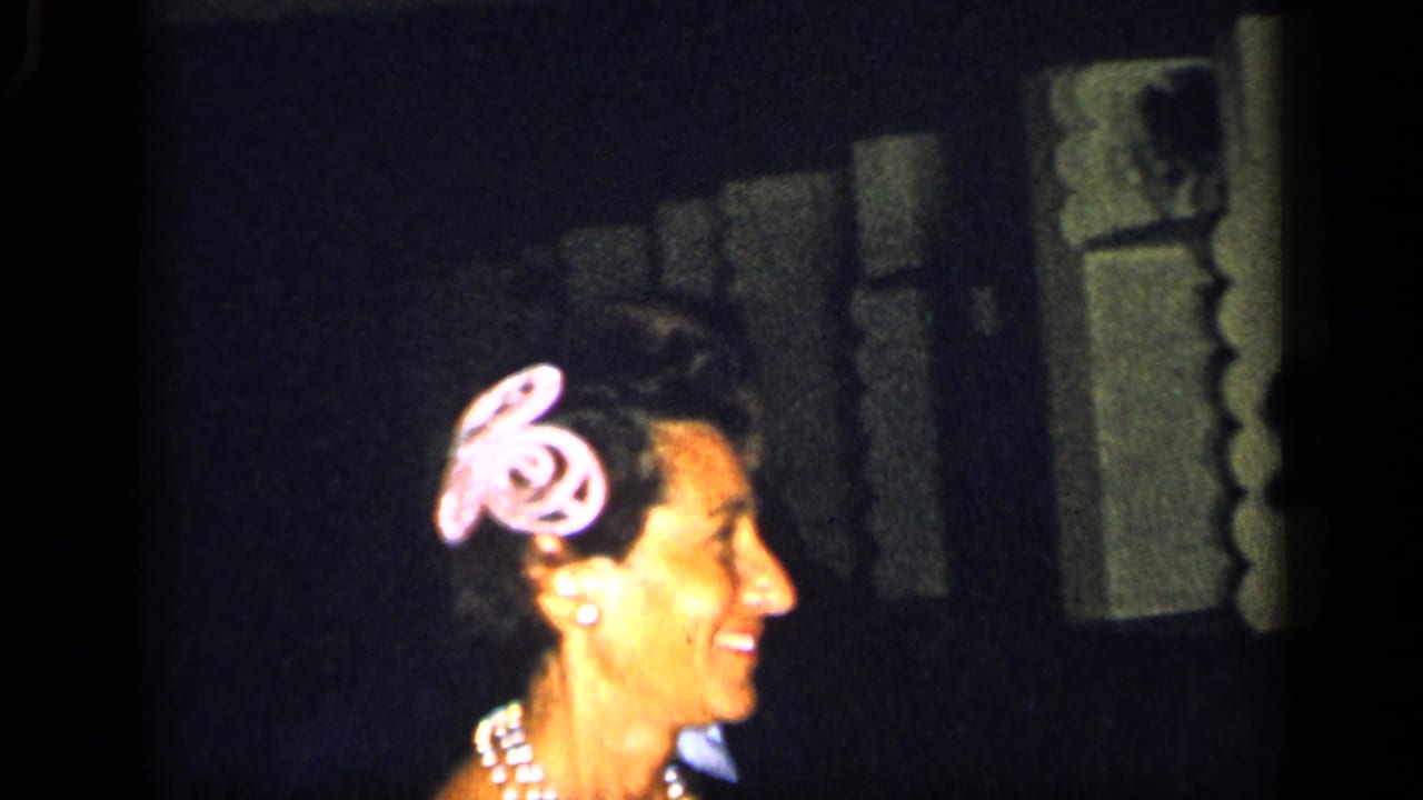 Woman with a pink hair accessory smiles beside a dim stage area.